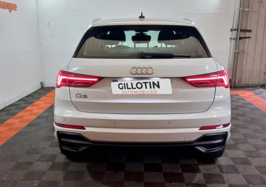 Vue arrière d’un Audi Q3 blanc 45 TFSI e 245 S tronic S line avec feux LED allumés en intérieur.