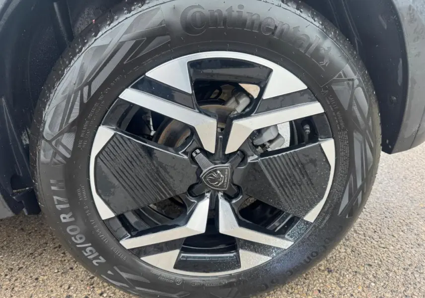 Gros plan sur la jante alliage 17 pouces noire et argentée du Peugeot 2008 Hybrid 145 gris, avec pneu Continental visible.