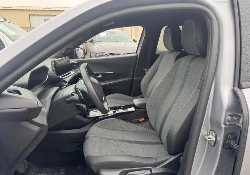 Vue intérieure côté conducteur du Peugeot 2008 gris 2025, montrant les sièges avant et le tableau de bord moderne avec écran tactile.
