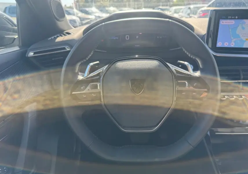 Vue rapprochée du volant noir du Peugeot 2008 Hybrid 136 e-DCS6 Allure avec écran tactile et cockpit numérique visible.
