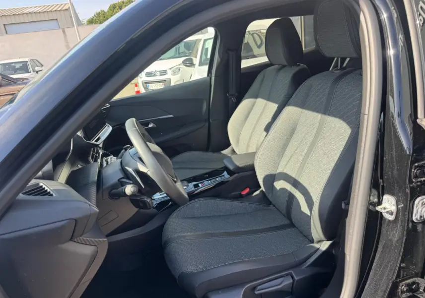 Vue intérieure côté conducteur du Peugeot 2008 Hybrid 136 Allure 2025 noir, montrant les sièges avant et le volant.