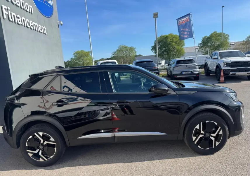 Profil droit d'un Peugeot 2008 Hybrid noir 2025 avec jantes alliage 17 pouces et barres de toit visibles en extérieur.