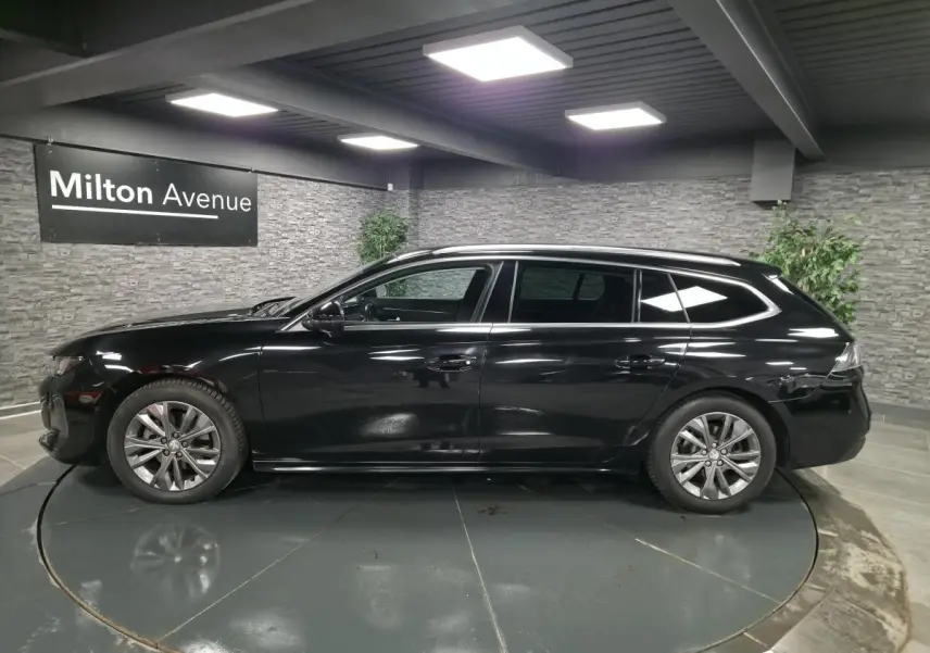 Peugeot 508 SW noire vue de profil côté gauche, avec barres de toit en aluminium et jantes alliage 17 pouces.