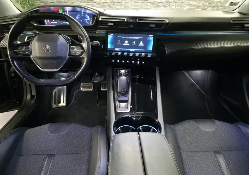 Vue intérieure avant de la Peugeot 508 SW noire, montrant le volant compact, l'écran tactile central et la console avec levier de vitesses.