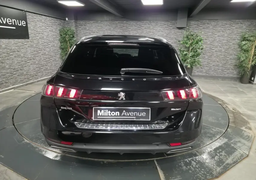 Vue arrière d'une Peugeot 508 SW noire avec feux arrière LED et double sortie d'échappement chromée.