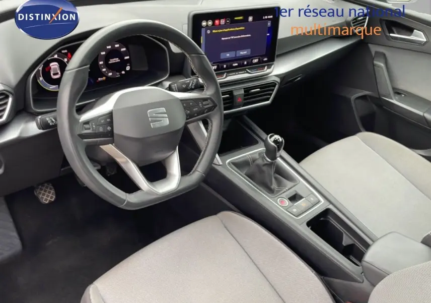 Vue intérieure de face du poste de conduite du SEAT Leon 2025, avec volant cuir multifonction et écran tactile central.