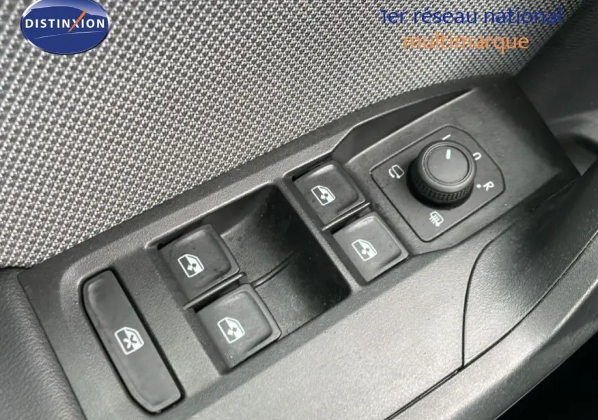 Gros plan sur les commandes des vitres et rétroviseurs côté conducteur d’une SEAT Leon gris métallique.