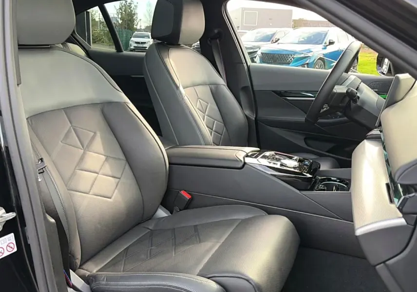 Intérieur avant droit de la BMW Série 5 i5 M60 2024, sièges cuir noirs avec surpiqûres et console centrale élégante.