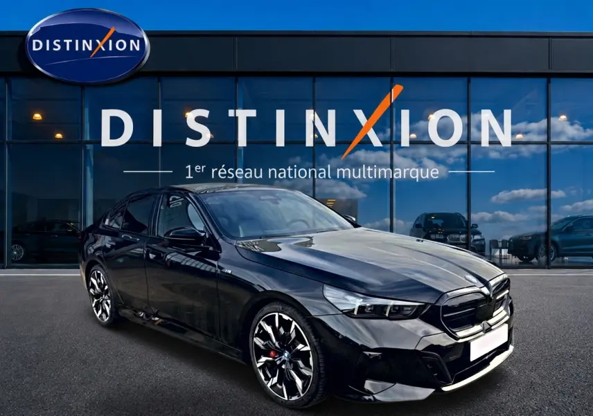 BMW Série 5 i5 M60 noir vue 3/4 avant droit, avec jantes alu bicolores et calandre noire distinctive.
