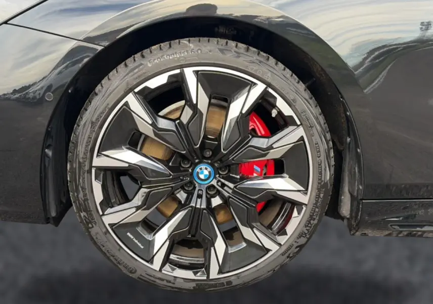 Gros plan sur la jante alu bicolore noire et argentée avec étrier de frein rouge d'une BMW Série 5 i5 M60 noir.