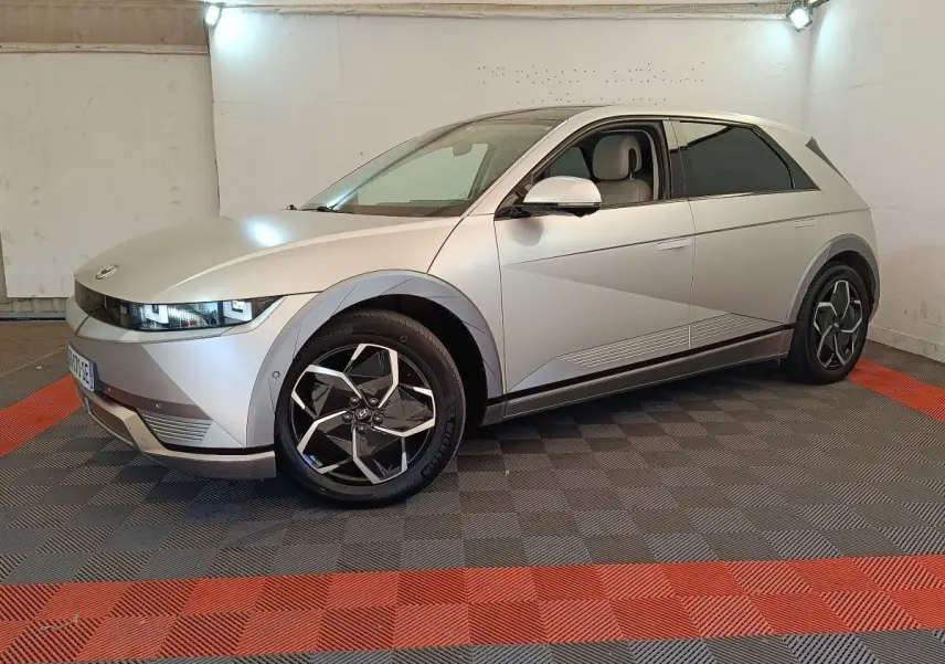 Hyundai IONIQ électrique beige vue 3/4 avant droit dans un garage avec jantes noires et grises distinctives.