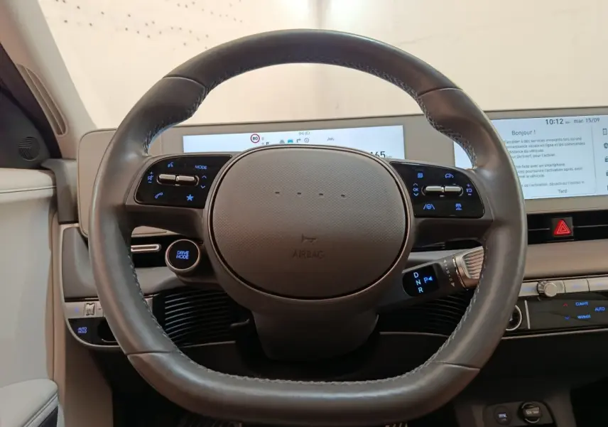 Vue frontale du volant cuir noir de la Hyundai IONIQ électrique 2023 avec tableau de bord digital et commandes intégrées.