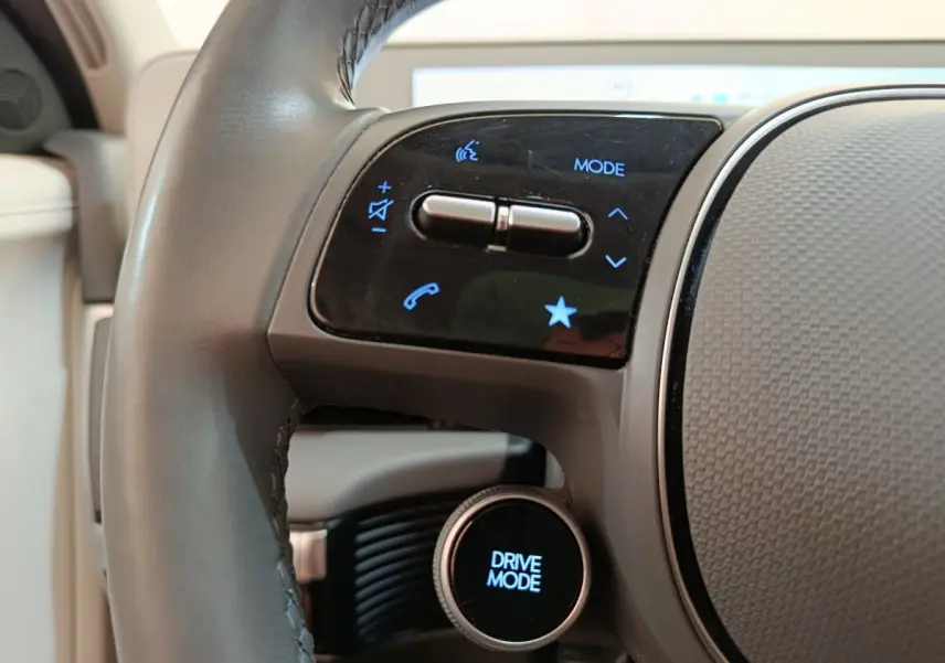 Gros plan sur le volant cuir beige de la Hyundai IONIQ 2023 avec commandes tactiles et bouton Drive Mode.