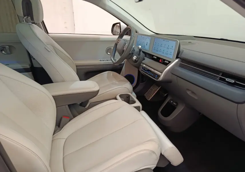Vue intérieure côté conducteur de la Hyundai IONIQ BEV 77KWH AWD Executive 2023 avec sièges beige et tableau de bord numérique.
