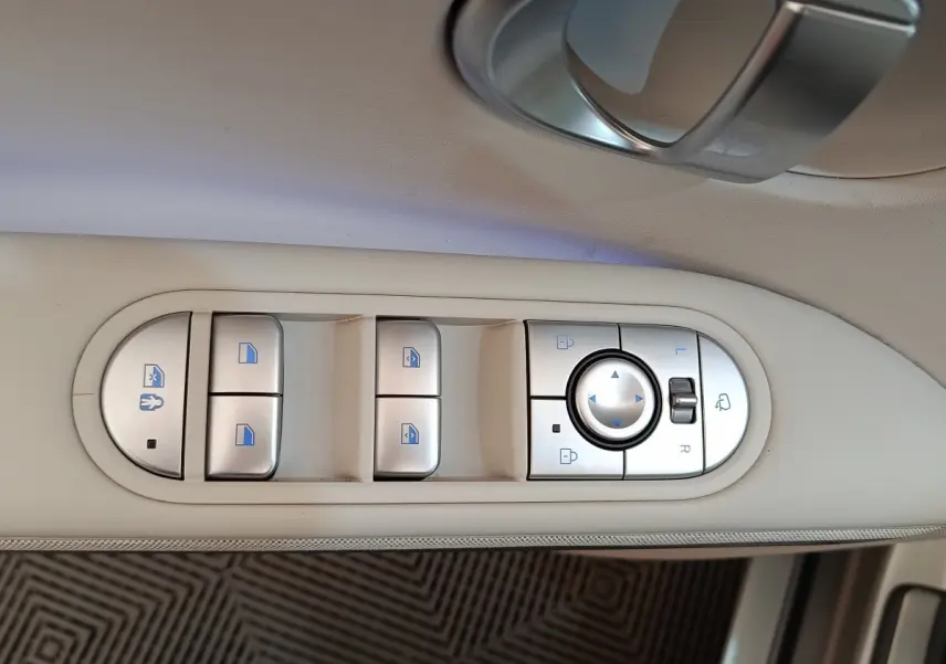 Gros plan sur les commandes de lève-vitres et rétroviseurs sur la porte beige intérieure d'une Hyundai IONIQ électrique 2023.