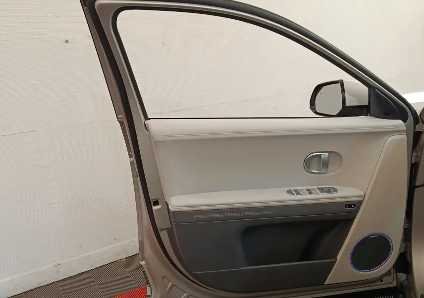 Vue intérieure de la porte avant gauche beige de la Hyundai IONIQ BEV 77KWH AWD Executive 2023 avec haut-parleur Bose.