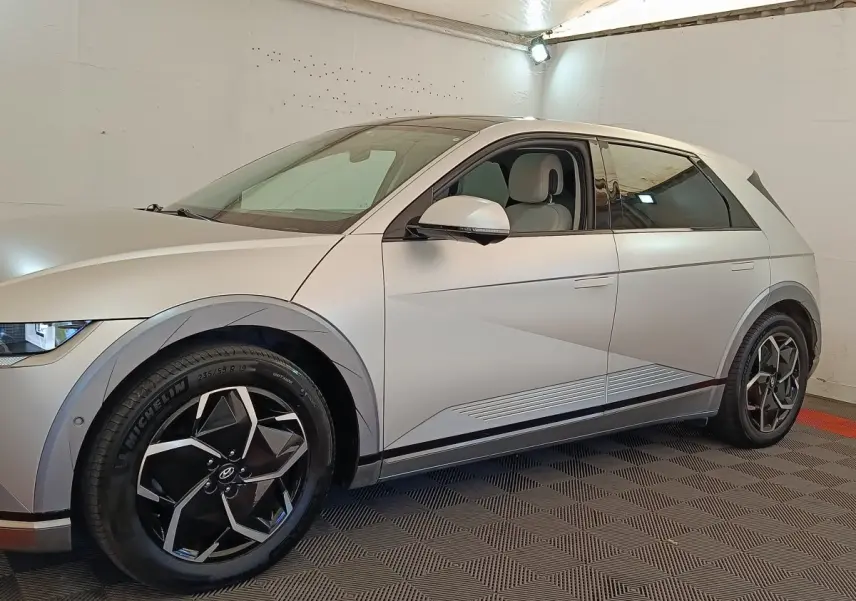 Vue latérale droite d'une Hyundai IONIQ électrique beige 2023 avec jantes noires et détails anguleux sur la carrosserie.