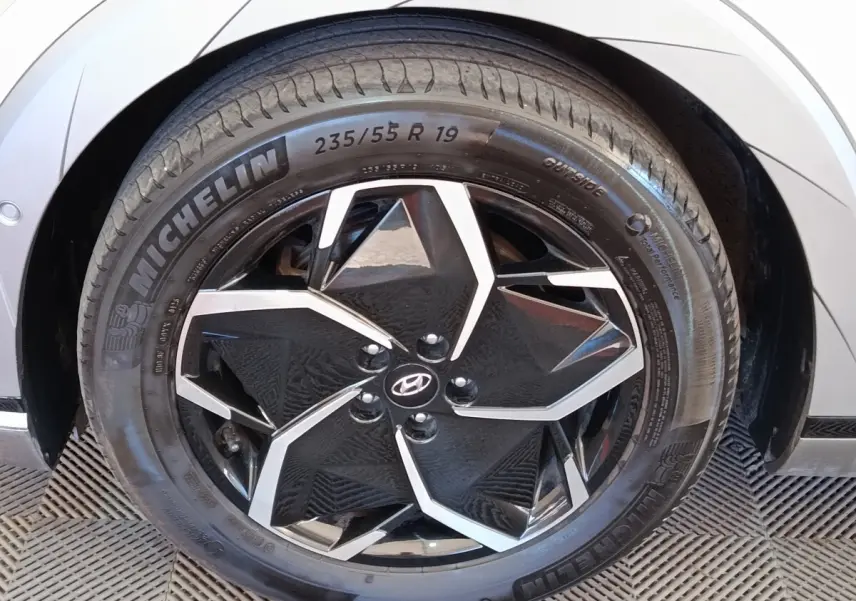 Gros plan sur la roue avant droite beige d’une Hyundai IONIQ BEV 77KWH AWD Executive avec jante noire et argentée.