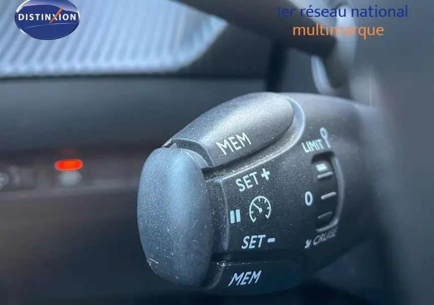 Gros plan sur la commande de régulateur de vitesse dans l'habitacle d'une Peugeot 208 électrique gris Artense.