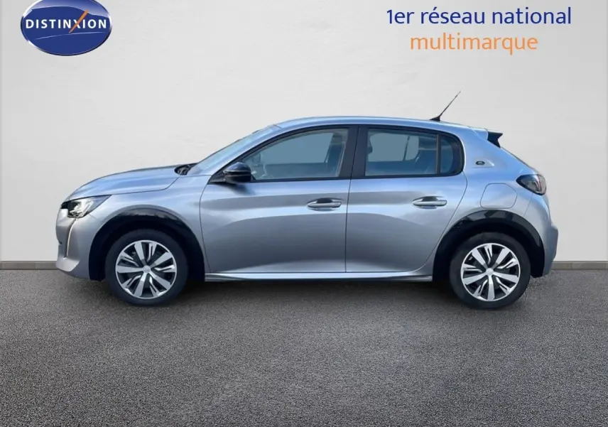 Profil côté gauche d'une Peugeot 208 électrique gris artense, version Active Business, garée devant un mur blanc.