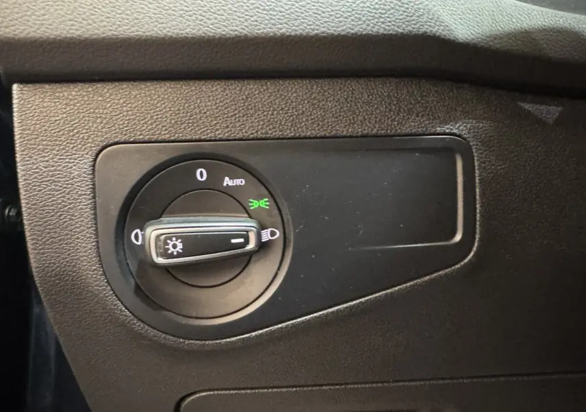 Gros plan sur la molette de commande des phares du Volkswagen Tiguan 1.5 TSI 150 DSG7 Life Business, intérieur noir.