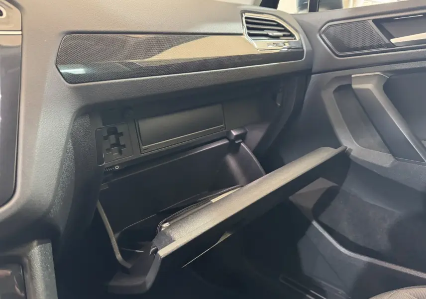 Vue intérieure côté passager du Volkswagen Tiguan 2021, boîte à gants ouverte avec finition noire et détails texturés.