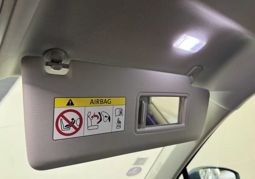 Détail intérieur du pare-soleil côté conducteur avec miroir et avertissement airbag, Volkswagen Tiguan bleu 2021.