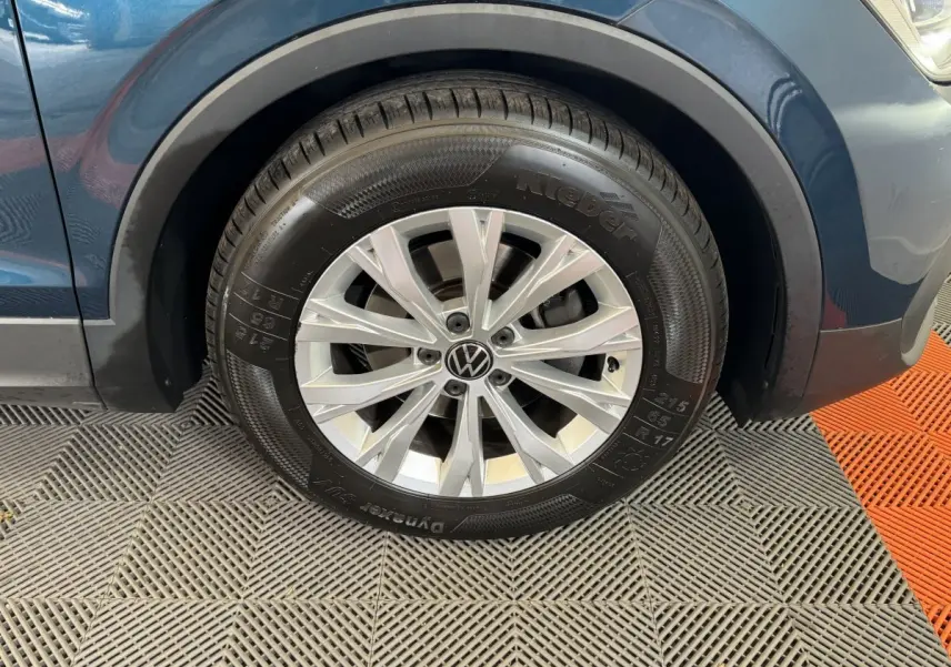 Gros plan sur la roue avant gauche d’un Volkswagen Tiguan bleu, avec jante alliage argentée et pneu Kleber.