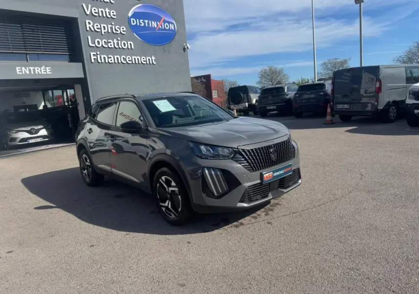 Peugeot 2008 Hybrid 145 gris en 3/4 avant droit, jantes alliage 17 pouces, devant un concessionnaire Distinxion.