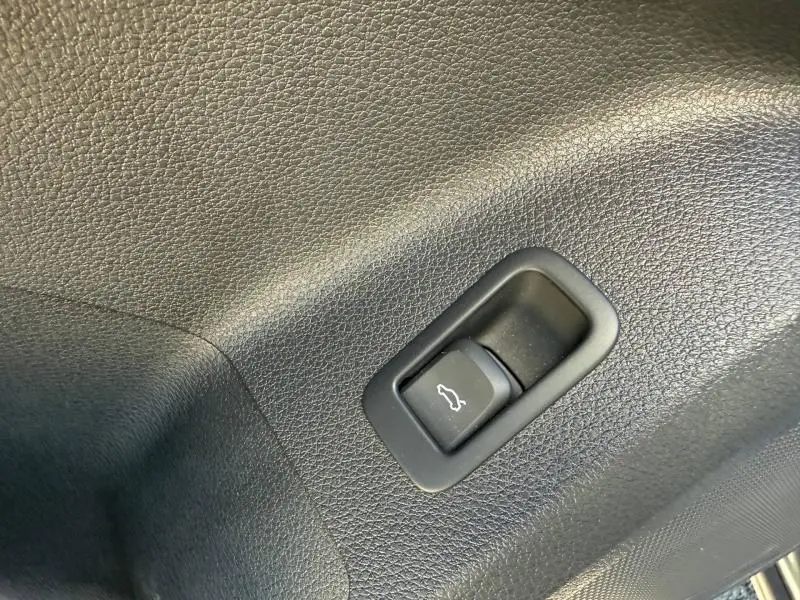 Gros plan sur le bouton d'ouverture du coffre dans l'habitacle de l'Audi Q2 35 TDI S line 2025 gris Daytona nacré.
