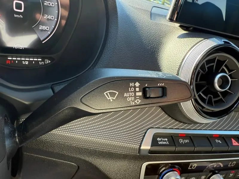 Gros plan intérieur sur la commande d’essuie-glace et la ventilation circulaire de l’Audi Q2 35 TDI gris Daytona nacré, tableau de bord partiel.