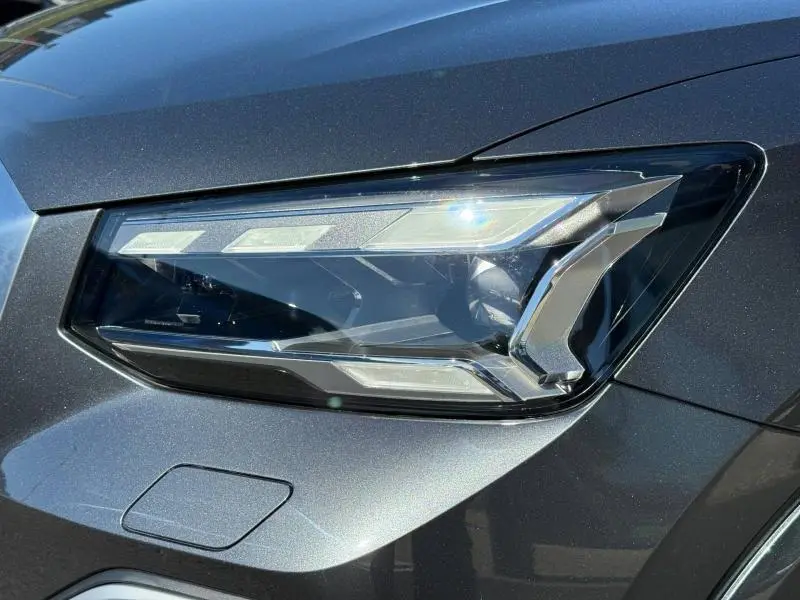 Gros plan sur le phare avant droit de l'Audi Q2 35 TDI S line 2025 en gris Daytona nacré, soulignant ses lignes modernes.