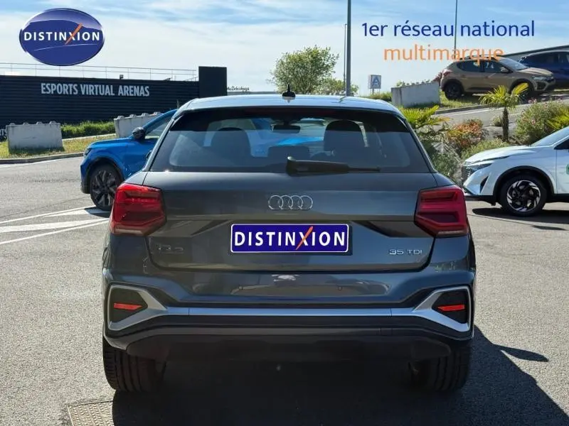 Vue arrière d'un Audi Q2 35 TDI gris Daytona nacré de 2025 avec logo S line et feux arrière rouges distinctifs.
