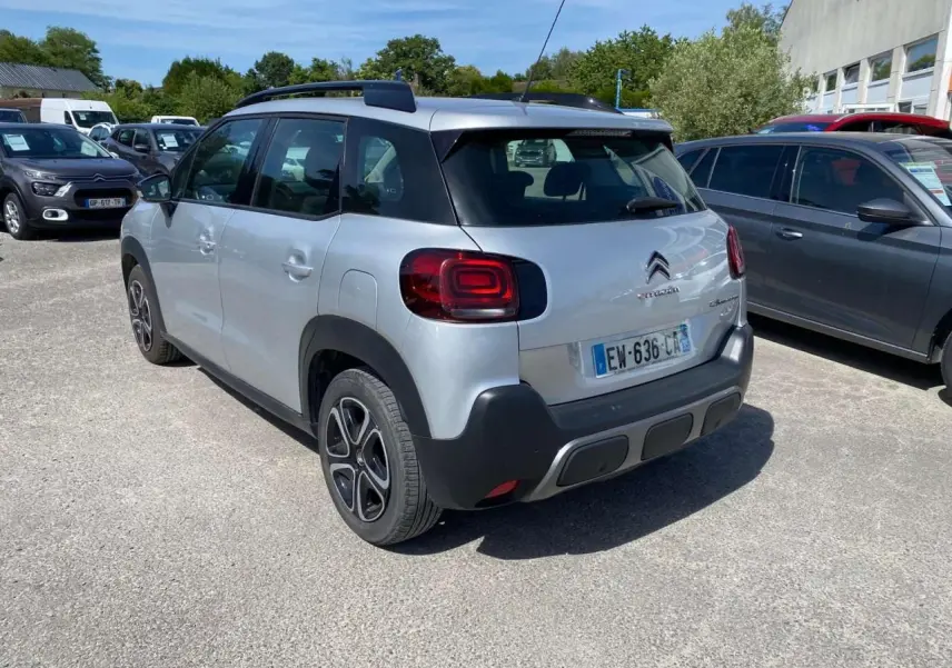 Vue 3/4 arrière droite d'un Citroën C3 Aircross gris Artense avec toit noir et jantes distinctives, stationné en extérieur.