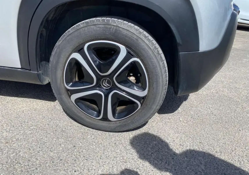 Gros plan sur la roue avant droite d'un Citroën C3 Aircross gris Artense avec protections noires autour des passages de roue.