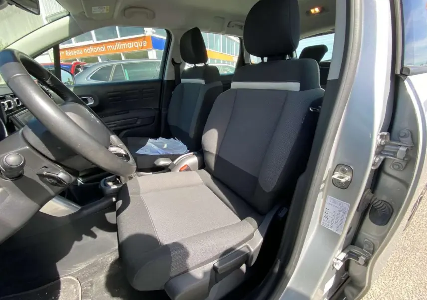 Vue intérieure côté conducteur du Citroën C3 Aircross gris Artense, montrant les sièges avant et le volant.