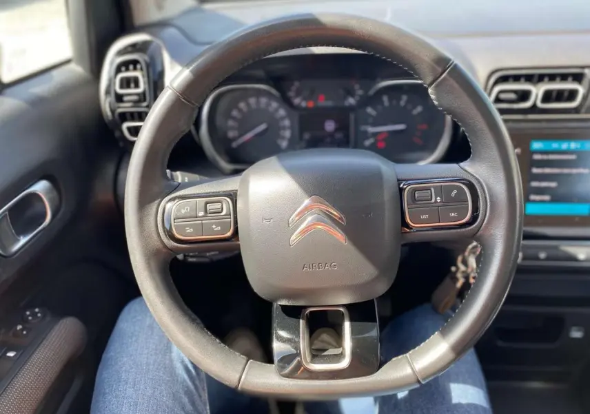 Vue rapprochée du volant noir du Citroën C3 Aircross 2018, avec commandes intégrées et tableau de bord en arrière-plan.