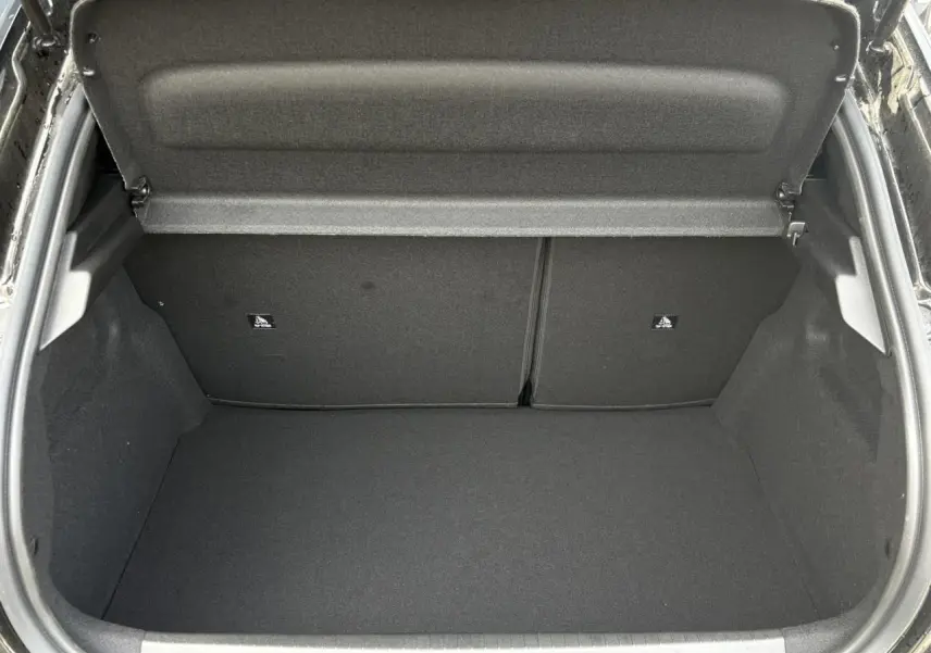 Coffre ouvert vu de l'arrière d'une Peugeot 208 Hybrid 110 e-DSC6 GT noir Perla, intérieur entièrement noir.