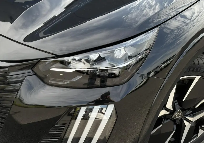 Gros plan sur l'avant droit noir Perla du Peugeot 208 Hybrid 110 e-DSC6 GT avec phares LED et jante diamantée 17''.