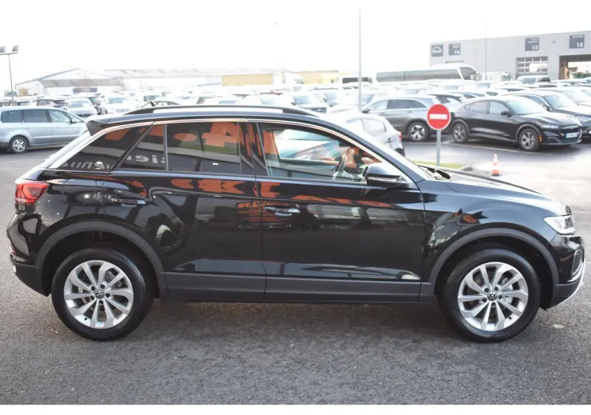 Vue latérale droite du Volkswagen T-Roc 2025 noir métallisé avec jantes alliage 17 pouces sur parking extérieur.