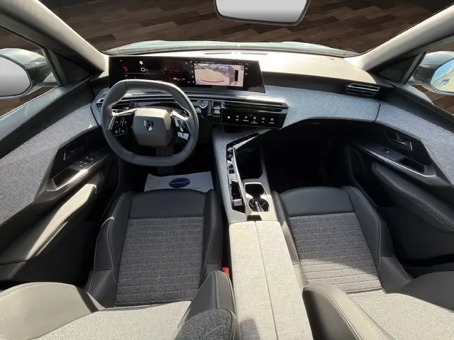 Vue intérieure avant du Peugeot 5008 2025 hybride, avec tableau de bord numérique et volant cuir multifonctions.