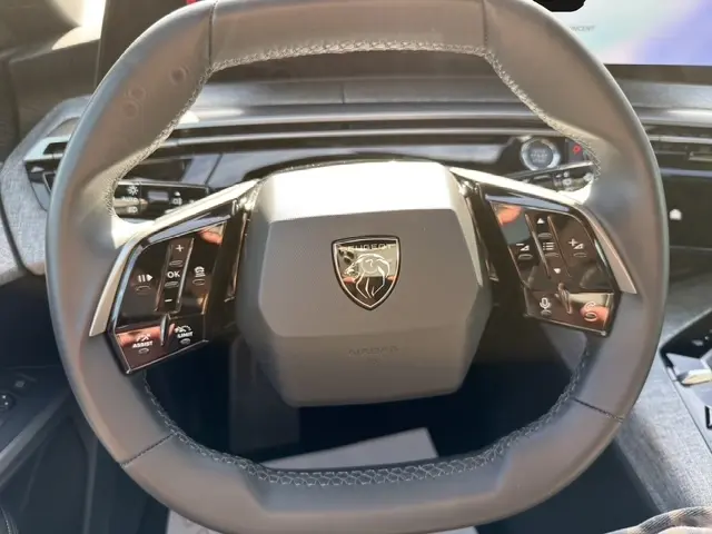 Vue rapprochée du volant cuir noir du Peugeot 5008 1.2 Hybrid 145 Allure, avec commandes multifonctions et logo central.