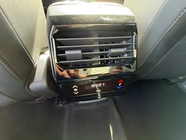 Vue rapprochée de la console arrière noire avec ventilation et commandes de climatisation du Peugeot 5008 bleu 2025.