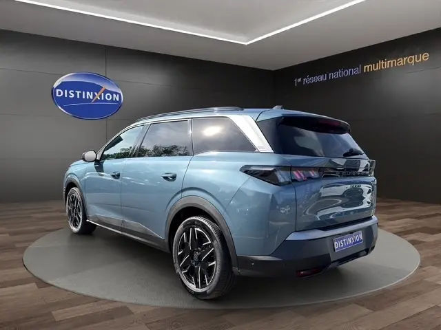 Peugeot 5008 bleu vue 3/4 arrière droit, SUV hybride avec jantes noires et toit contrasté blanc.