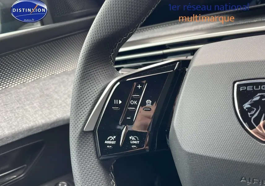 Gros plan sur le volant cuir perforé côté gauche du Peugeot 3008 Hybrid 145 gt e-dcs6 bleu obsession, boutons multifonctions visibles.