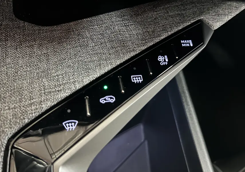 Gros plan sur les commandes tactiles de la climatisation du Peugeot 5008 III Hybrid 145, avec finition tissu gris.