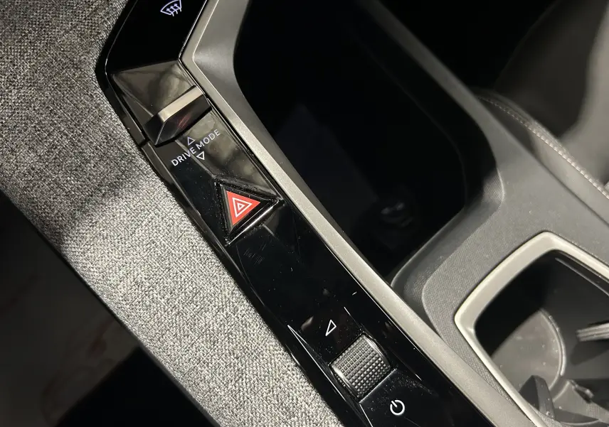 Gros plan sur la console centrale du Peugeot 5008 gris Artense, mettant en valeur les commandes Drive Mode et le bouton de warning triangulaire rouge.