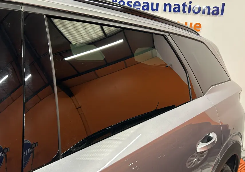 Vue latérale droite sur la porte arrière d’un Peugeot 5008 gris Artense avec vitres teintées en intérieur showroom.