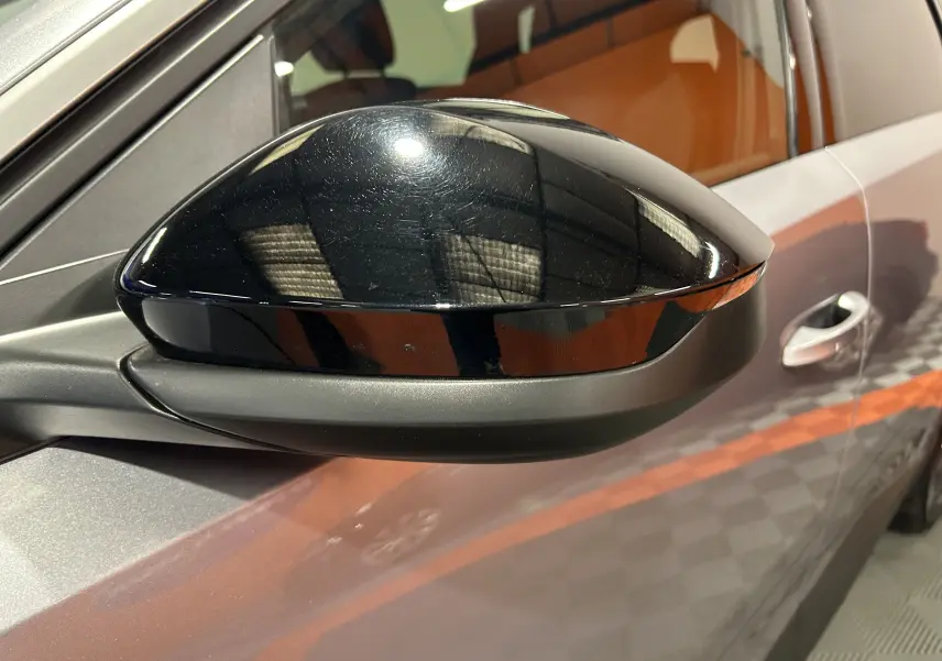 Rétroviseur noir brillant côté gauche du Peugeot 5008 gris Artense, vue rapprochée sur la portière avant.