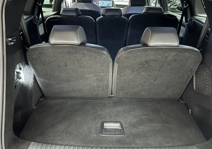 Vue intérieure arrière du coffre du Peugeot 5008 gris Artense avec sièges rabattus et banquette 3e rangée visible.
